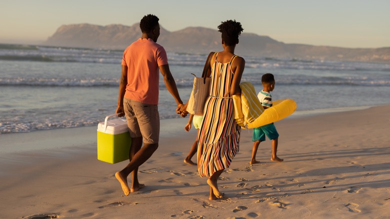 Family walking on beach with cooler