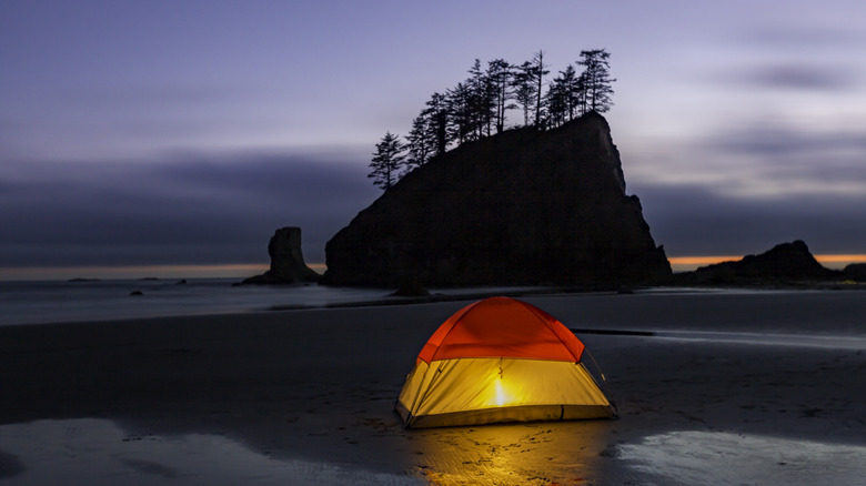 A rock formation and glowing tent