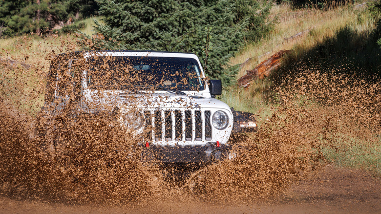 A white jeep driving through mud on mountain roads