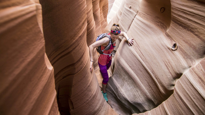 woman climbing through Zebra Slot Canyon in Utah