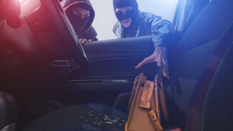 Burglars stealing purse from inside of car