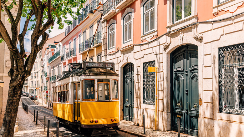 Yellow tram passing through buildings in Lisbon