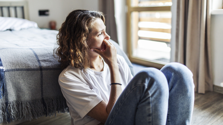Worried woman sitting by bed