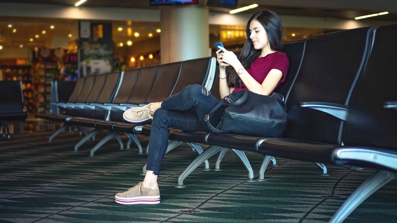 Woman in smiling on phone in deserted airport lounge