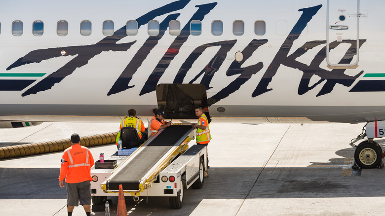 People unloading luggage from an Alaska Airlines flight