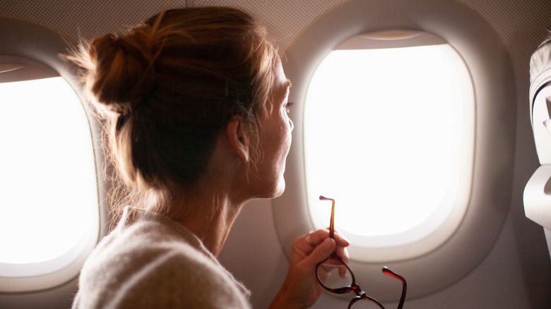 Woman with hair in a bun looking out an airplane window