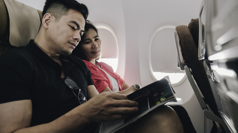 Couple on a flight reading a magazine