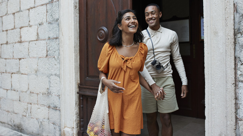 Man and woman leaving door to building laughing