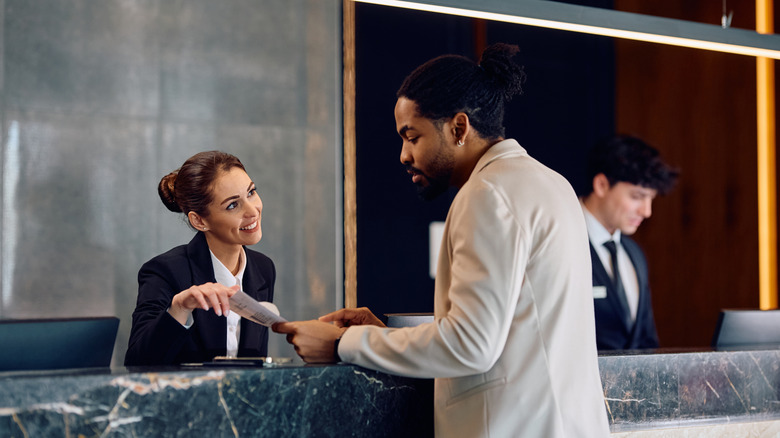 Guest at hotel front desk talking to hotel and looking at document