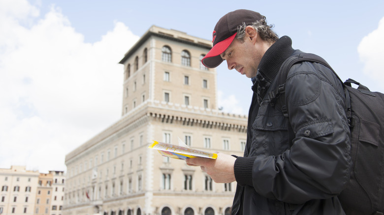 Man looking at map with historical European building in background