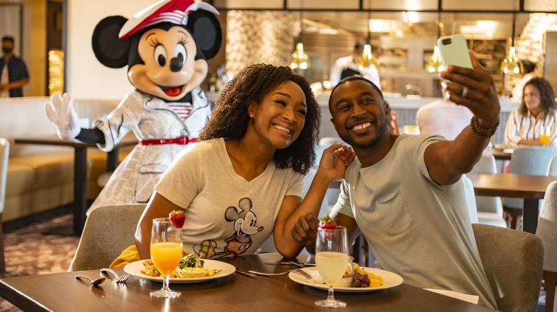 A happy couple smiling and taking a photo inside a Walt Disney restaurant