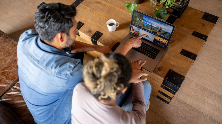 A couple planning their vacation on a computer viewed from above