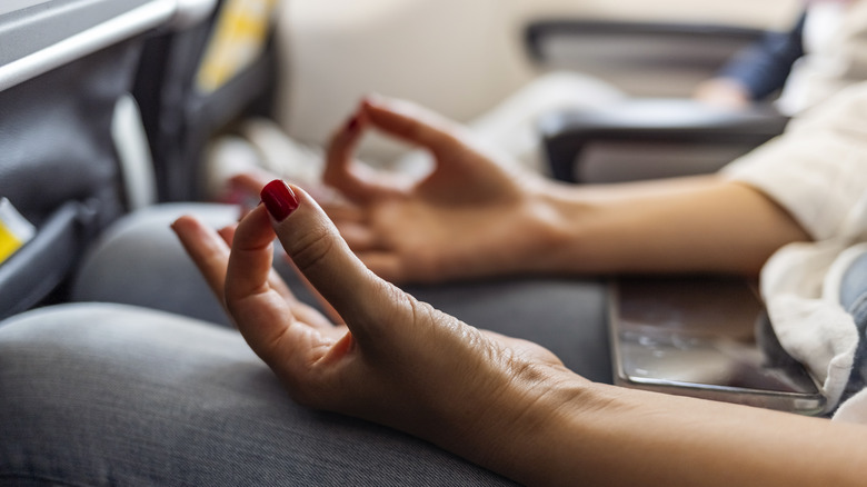 Person meditating in plane seat