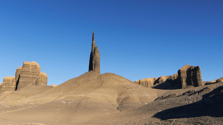 Dusty dirt road through desert and spire