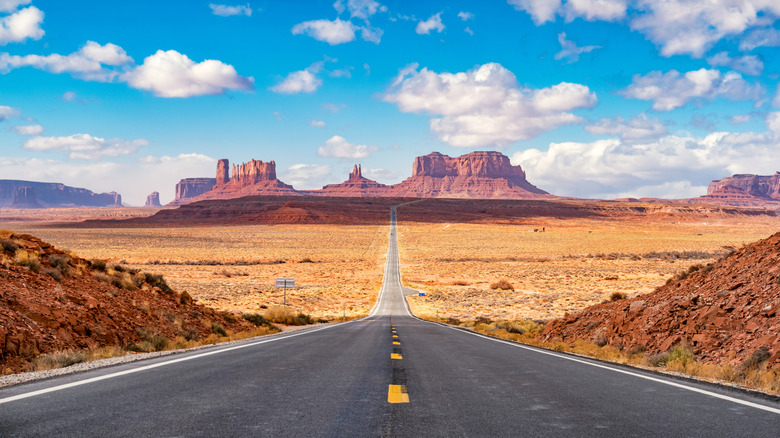 A two-lane Utah road with canyons in the distance