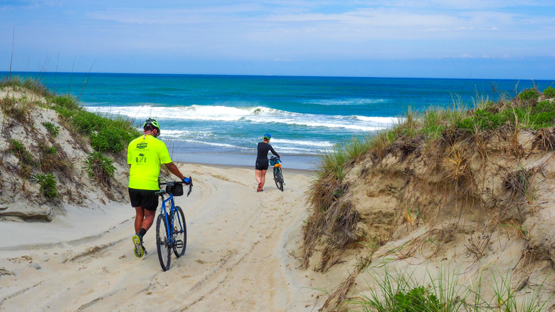 Two cyclists wheeling their bikes on an empty beach