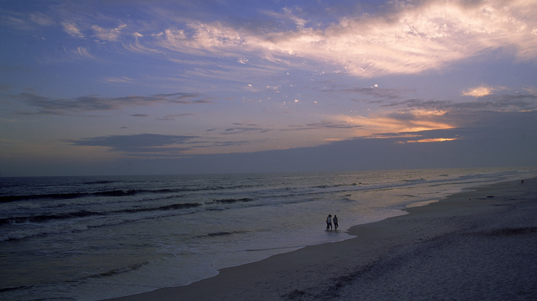 Three people walking on deserted beach