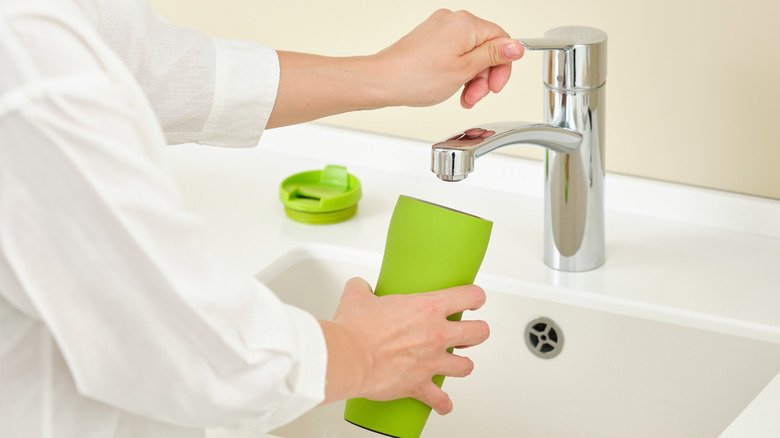 Woman washing a thermos reusable bottle