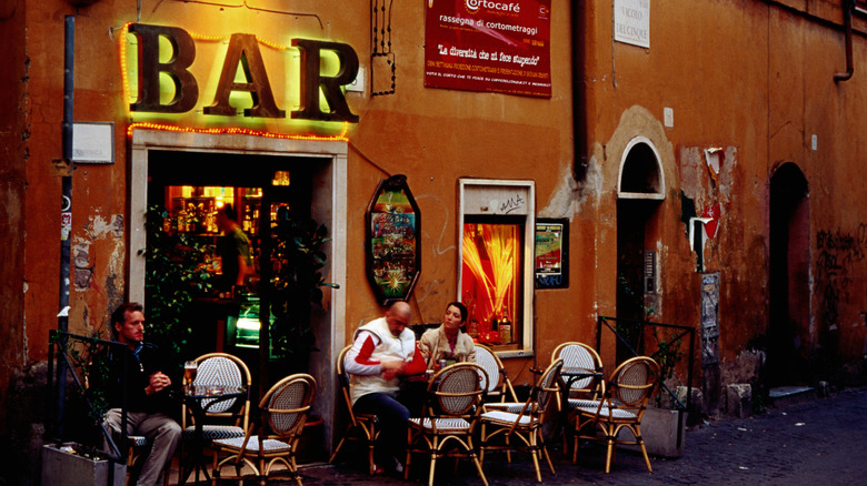 Italian bar with outdoor sign and tables in the evening