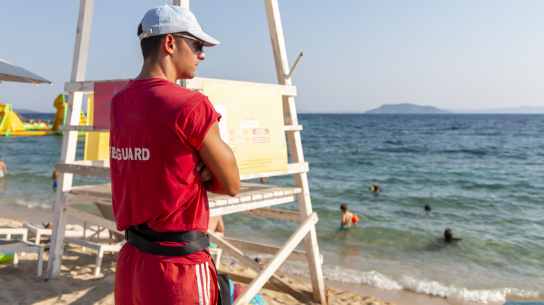 Lifeguard watching the water next to a lifeguard stand