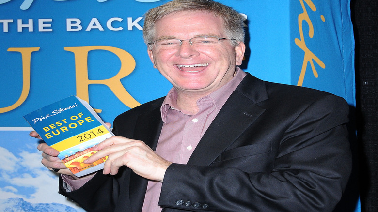 Travel writer Rick Steves smiles while holding one of his books