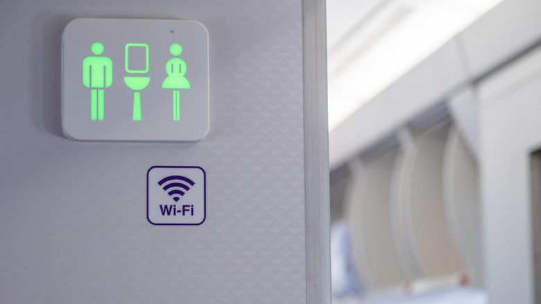 Signage for the bathroom on an airplane, illuminated green to indicate a vacancy.