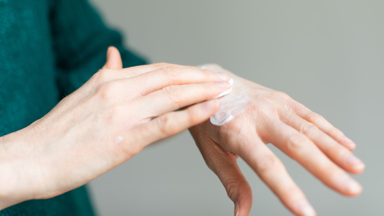 Woman putting lotion on hand 