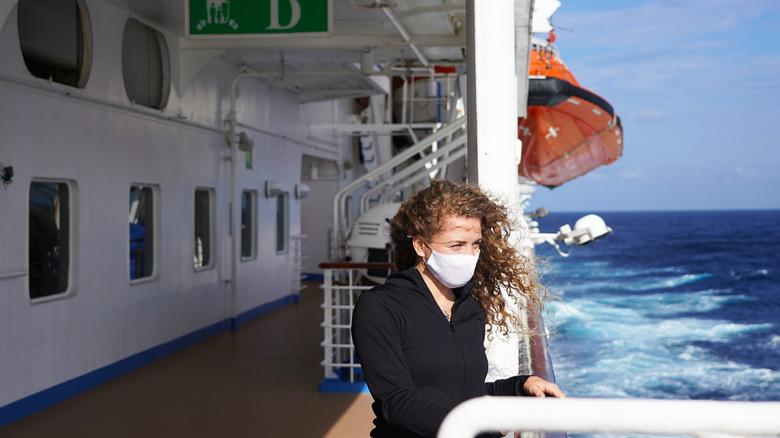 A woman on a cruise deck wearing a surgical mask