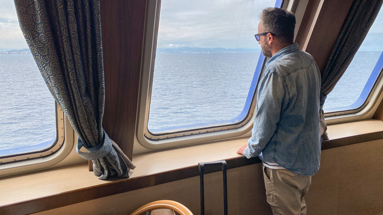 A man looking out the window of a cruise ship