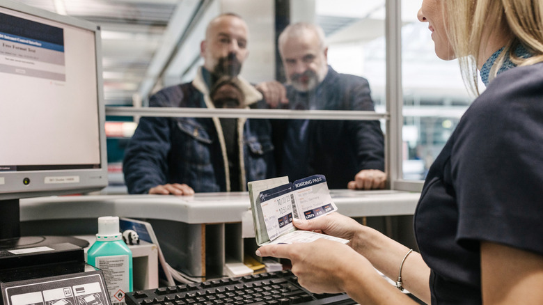 A couple showing their boarding passes to the gate agent