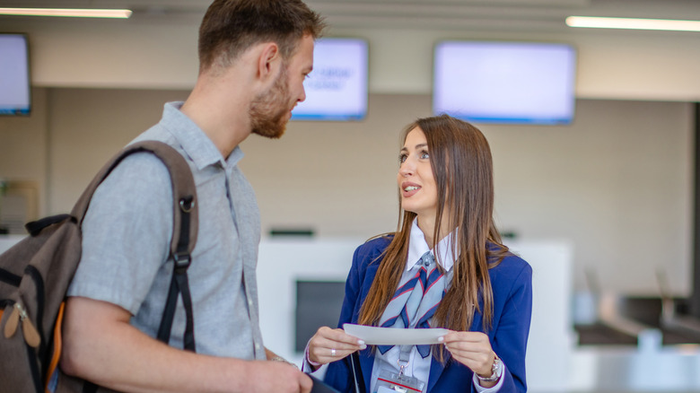 An airline employee helps a passenger with their boarding pass at the airport