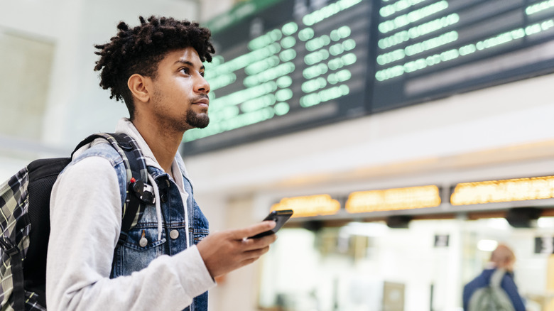 man holding phone in airport