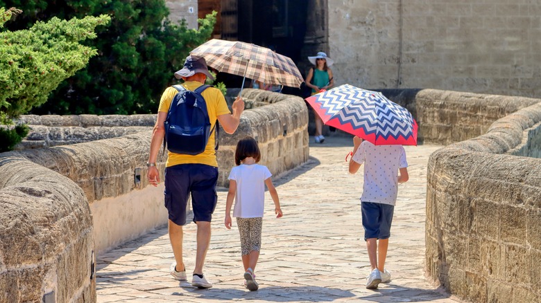Family carrying sun umbrellas