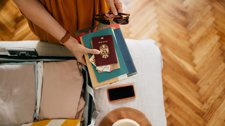 person holding passport over suitcase