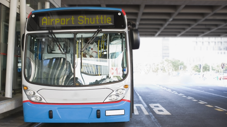 An airport shuttle drops off passengers at the terminal