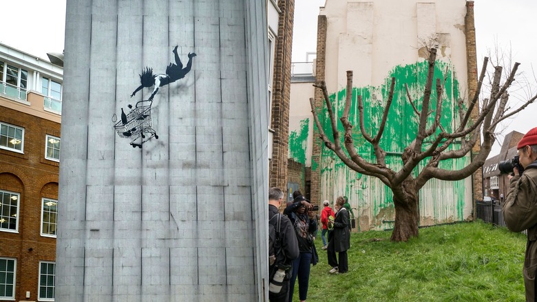 Falling Shopper by Banksy and tree painting by Banksy