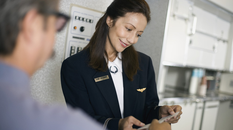 Flight attendant assisting a passenger with boarding