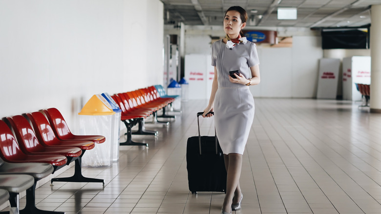 Flight attendant walking in airport with luggage