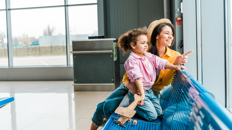 mother and daughter look out airport window