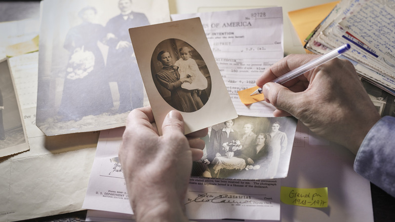 writing notes on table full of old family photos and immigration records