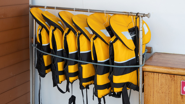 yellow life jackets hung on a rack on a ship deck