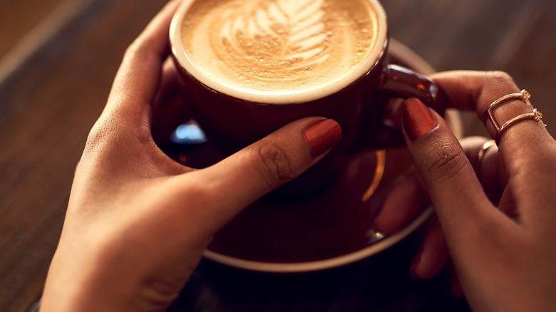 female hands holding cappuccino mug