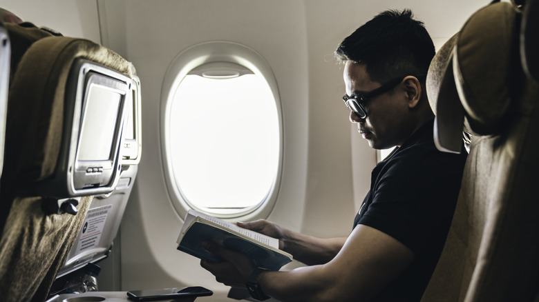 Passenger reading a book during a flight