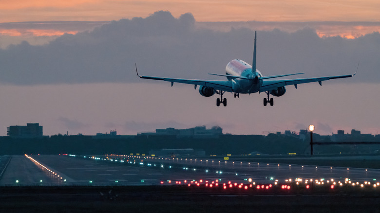 An airplane approaches the runway for landing at sunrise