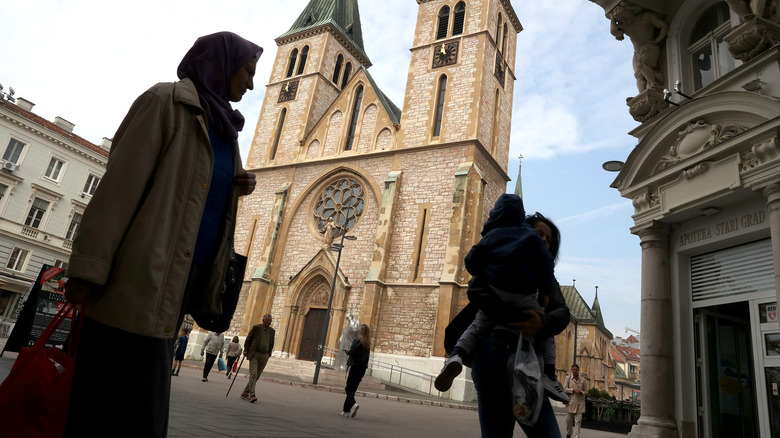 Individuals walking around a Catholic Cathedral in Sarajevo