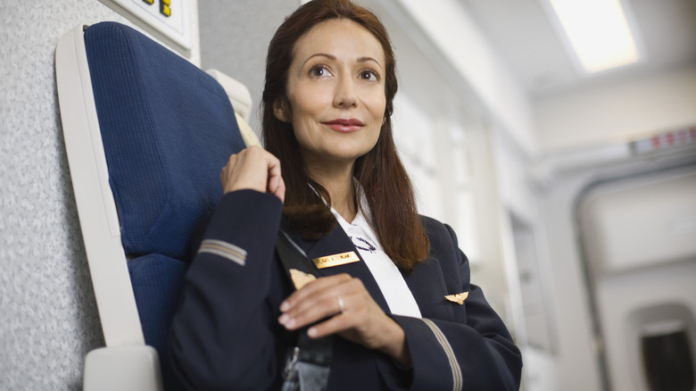 Flight attendant buckling into her seat