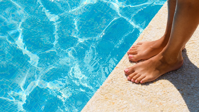 People dipping their feet in a swimming pool