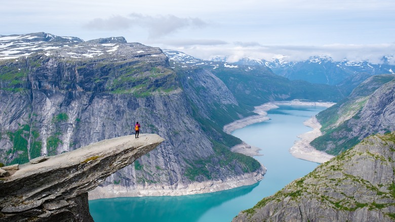 Hiker on the Trolltunga ledge above a lake