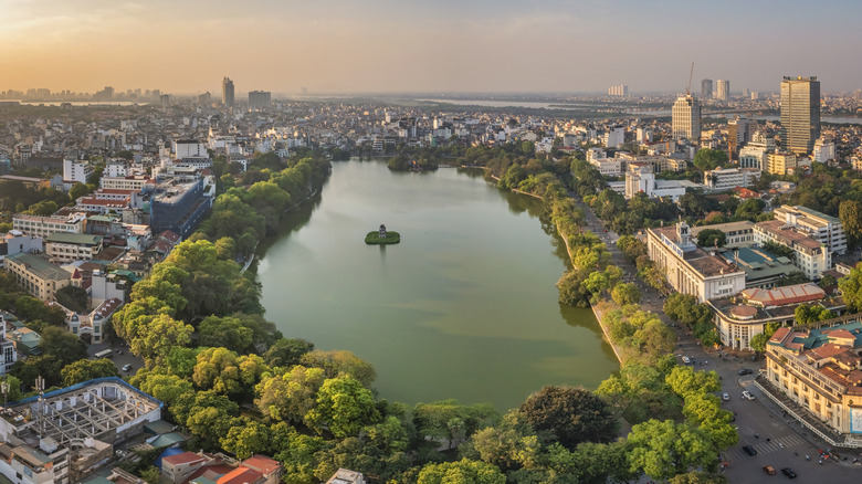 Aerial view of lake surrounded by green trees in the middle of Hanoi