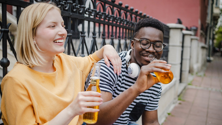 Cheerful young people drinking on the street